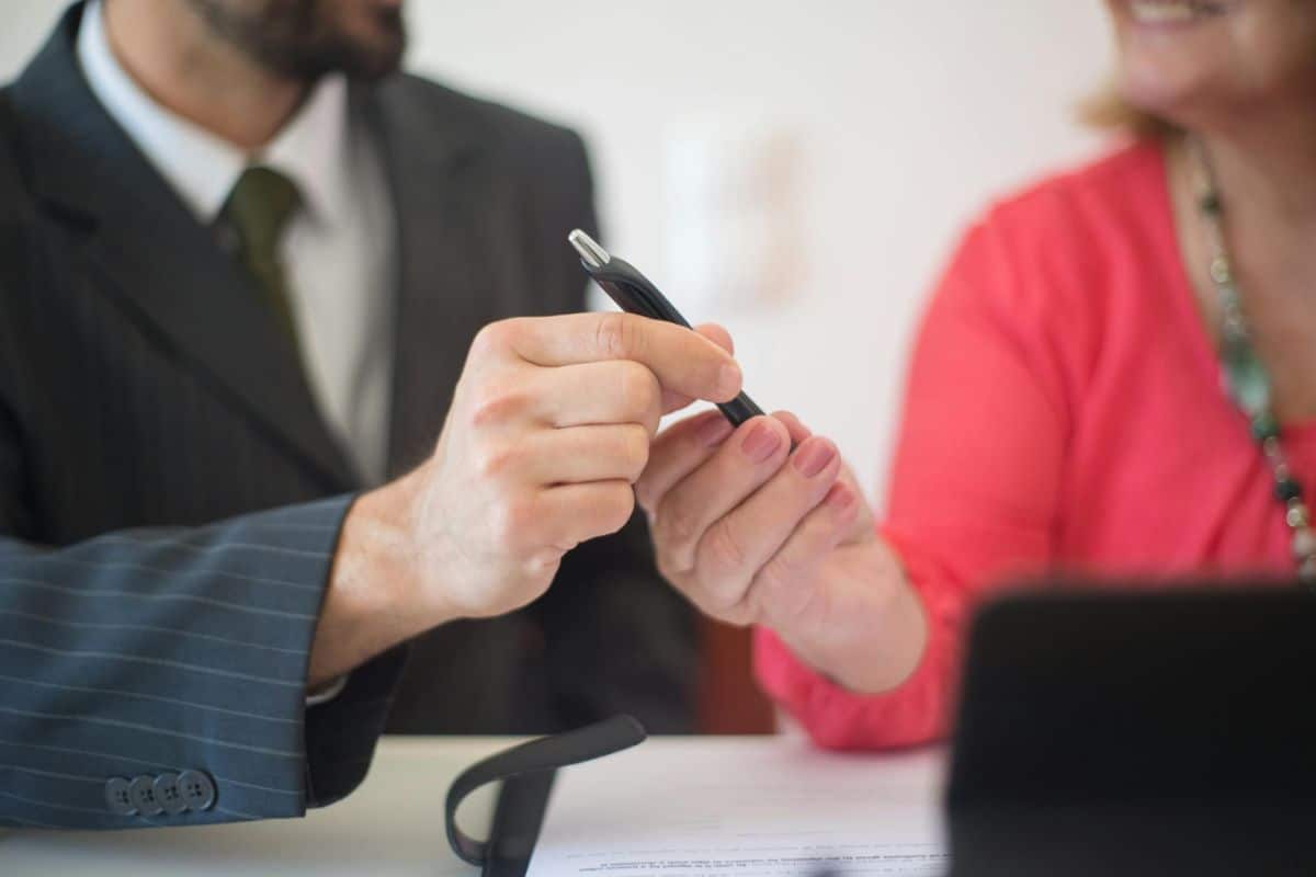 Stock image of a man and woman both holding a pen together